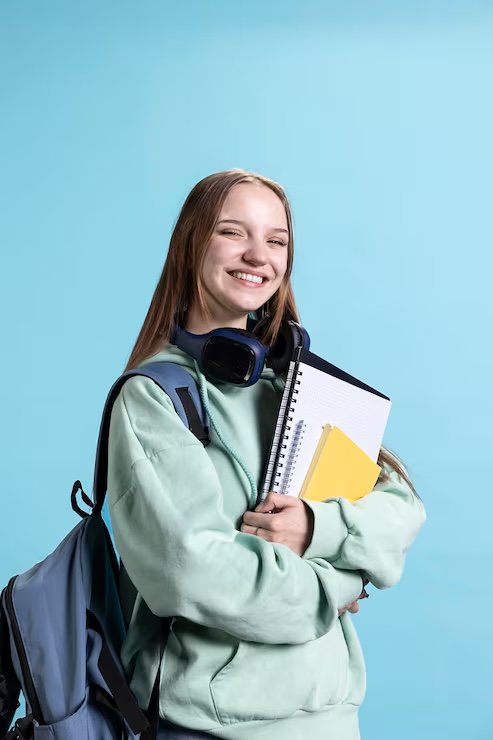 A smiling student holding notebooks and a backpack